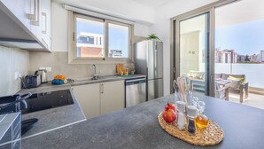 A modern kitchen with a built-in oven, a refrigerator, and a window overlooking a cityscape. - Mulberry Court Premium Apartments (Limassol)