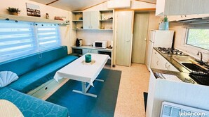 A compact kitchen with a dining area, a microwave, a stove, and a sink. - Air-conditioned mobile home, 5-minute walk from Lac de Biscarrosse "Menthe à l'eau" lake (Biscarrosse)