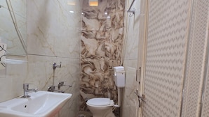 Une salle de bain avec un mur en marbre, un lavabo, des toilettes et un espace douche.