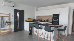 Cocina moderna con una isla central, taburetes de bar y un microondas.