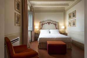 Une chambre d’hôtel avec un grand lit, deux lampes de chevet, une chaise et une petite table.