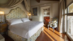 A bedroom with a large bed, a nightstand, a chair, and a window with curtains.