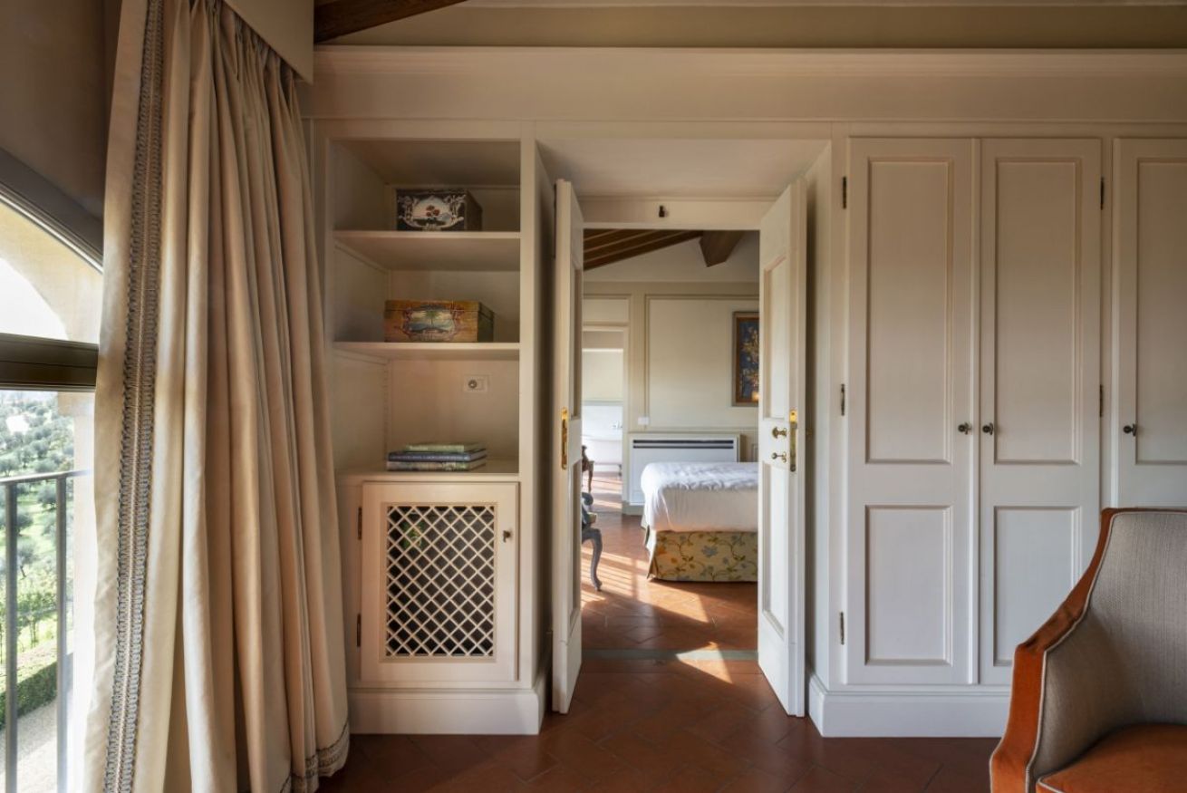 A bedroom with a bed, a wardrobe, and a small cabinet with a lattice front.