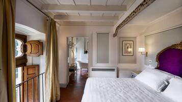 Een hotelkamer met een groot bed, een houten hoofdbord, een badkamer met een bad en een balkon met een leuning.