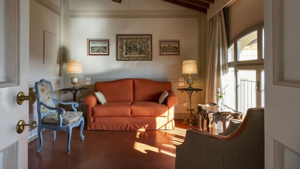 A living room with a sofa, a chair, and two lamps. There are three framed pictures on the wall.