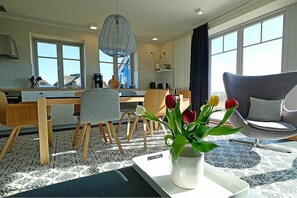 Cozy living area with a dining table for two, comfortable sofa, and large windows.