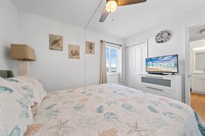 Relax in a serene bedroom with a large bed, flat-screen TV, and ceiling fan.