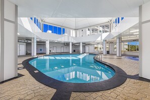 Relax by the oval-shaped pool surrounded by a patterned tile floor and high ceiling with white beams.