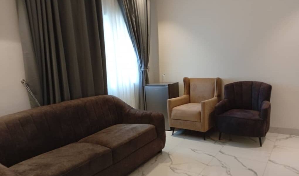 A living room with a brown sofa, a beige armchair, and a dark armchair.