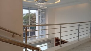 Un interior moderno con una escalera, una lámpara decorativa y vistas a través de un amplio ventanal.