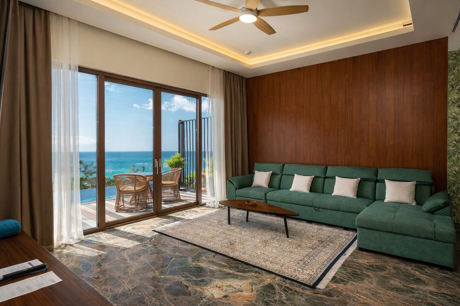 A modern living room with a green sofa, a wooden coffee table, and a view of the ocean through large sliding doors.