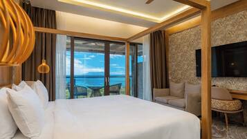 Een hotelkamer met een groot bed, een televisie, een zithoek en uitzicht op de oceaan.