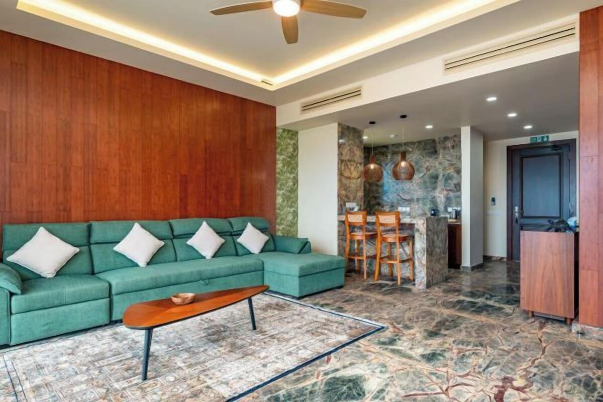 Una sala de estar moderna con un sofá modular, una mesa de centro y un comedor con candelabro.