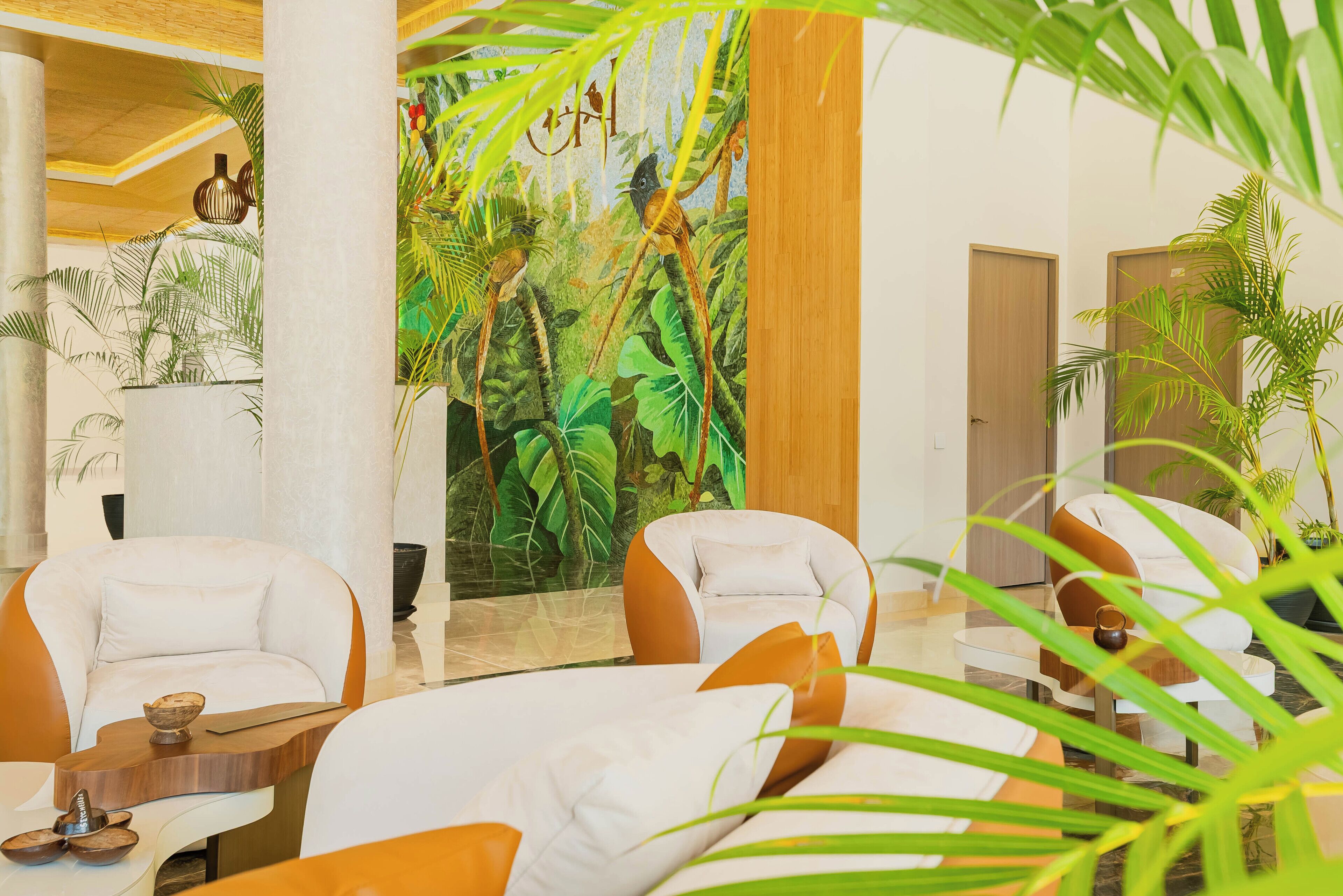A lobby with two white armchairs, a wooden coffee table, and a mural of a jungle scene.