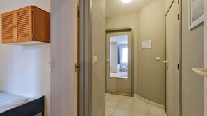A room with a bed, a wooden cupboard, and a door leading to a bathroom. - Apartment in Blankenberge near the Beach (BLANKENBERGE)