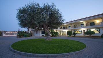 Un edificio con un cortile centrale, un albero grande e un prato curato.