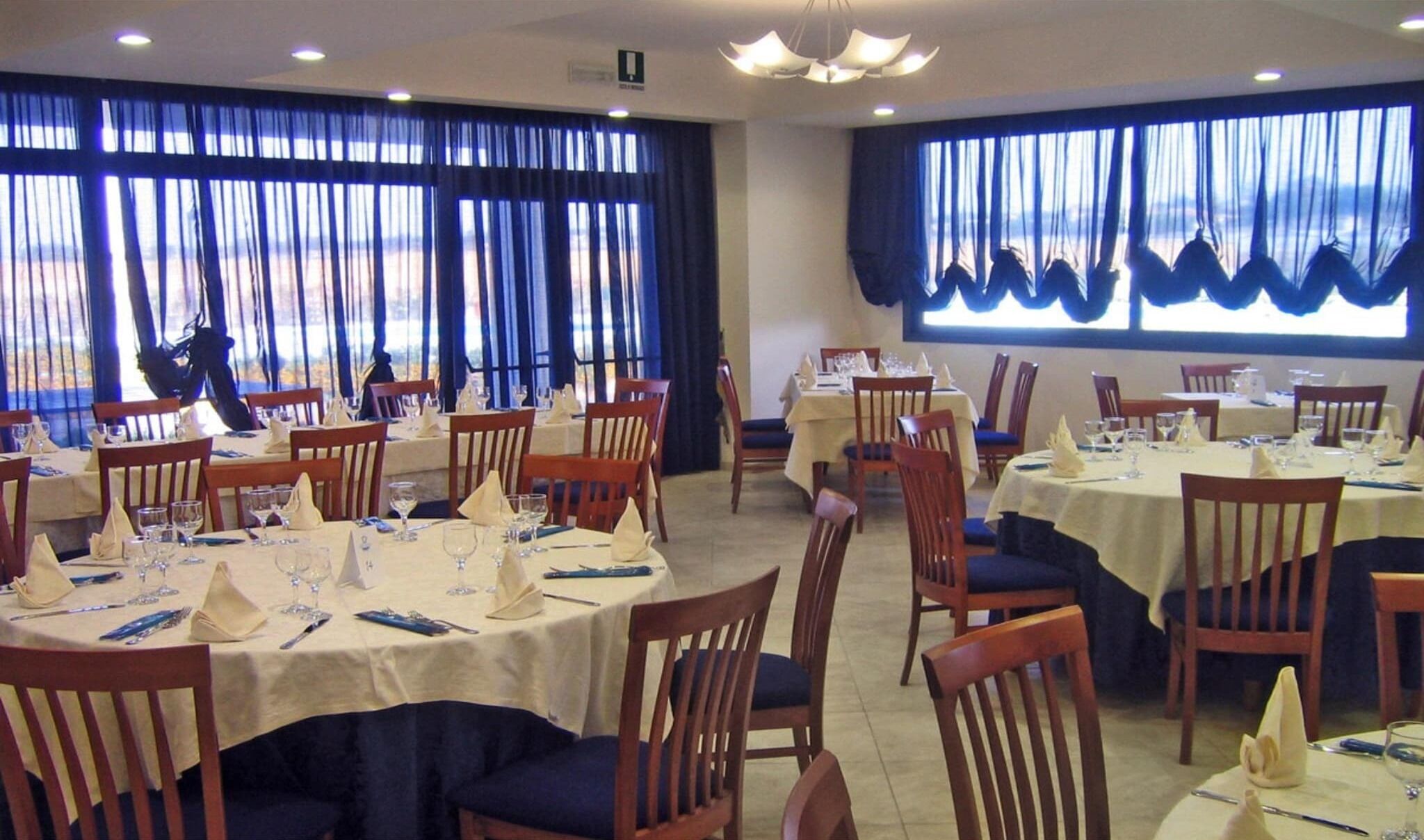 Un ristorante con tavoli rotondi, sedie e tende blu.