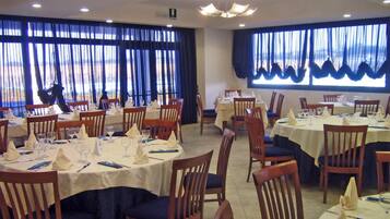 Un ristorante con tavoli rotondi, sedie e tende blu.
