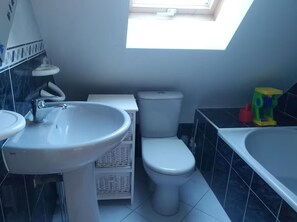 Ein Badezimmer mit Oberlicht, Waschbecken, Toilette und Badewanne.