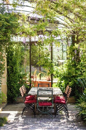 Ein Garten mit Terrassenmöbeln, umgeben von üppigem Grün und violetten Blumen.