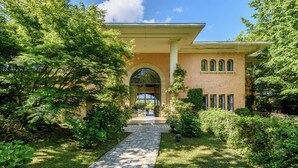 A building with a stone pathway leading to an arched entrance, surrounded by lush greenery. - Exceptional villa between sea and mountains in a private estate in Saint Jean de Luz (Saint-Jean-de-Luz)