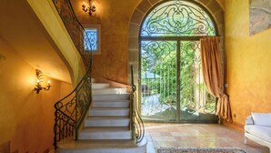 A grand staircase with ornate metal railings leading to a large glass door with a view of greenery outside. - Exceptional villa between sea and mountains in a private estate in Saint Jean de Luz (Saint-Jean-de-Luz)
