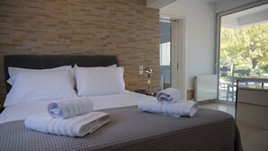 Et hotelværelse med en murstensvæg, en seng med hvide sengetøj og udsigt til det fri.
