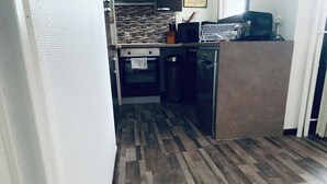 Una cocina con suelo de madera, microondas, refrigerador y estufa.