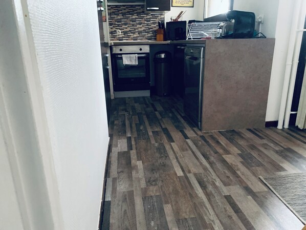 A kitchen with a wooden floor, a microwave, a refrigerator, and a stove.
