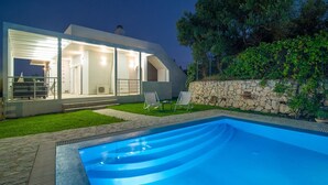 Een modern huis met een zwembad, een stenen muur en een terras.