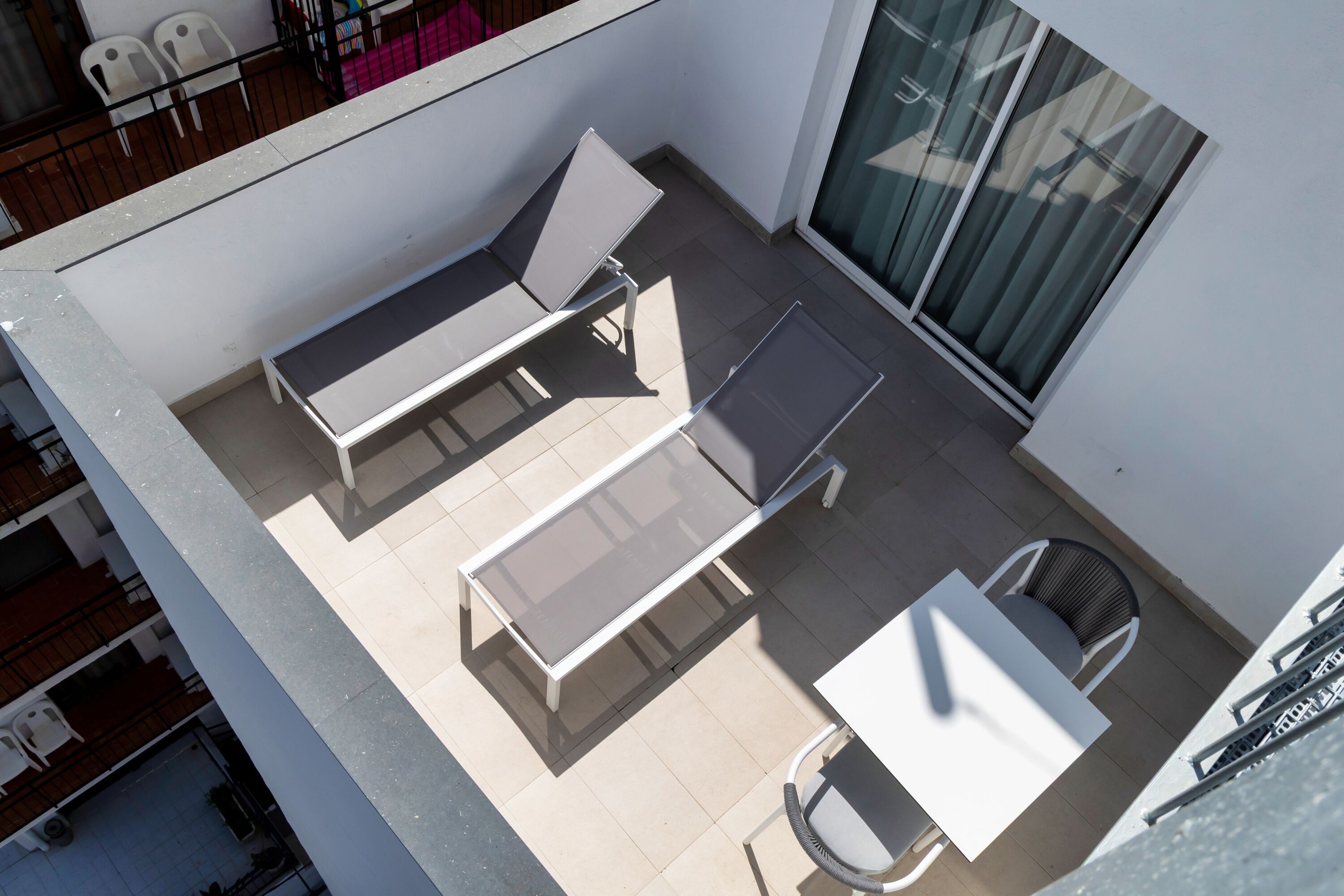 Terraza en la azotea con dos tumbonas, una mesa y una silla.