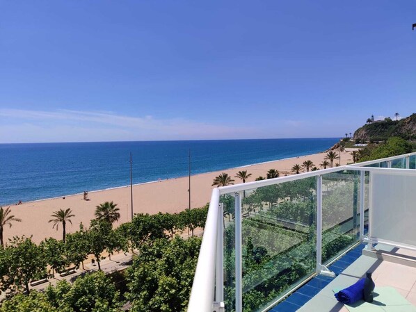A balcony with a view of a beach, palm trees, and a clear sky. - Hotel Calella by Beatriz Hoteles (Calella)