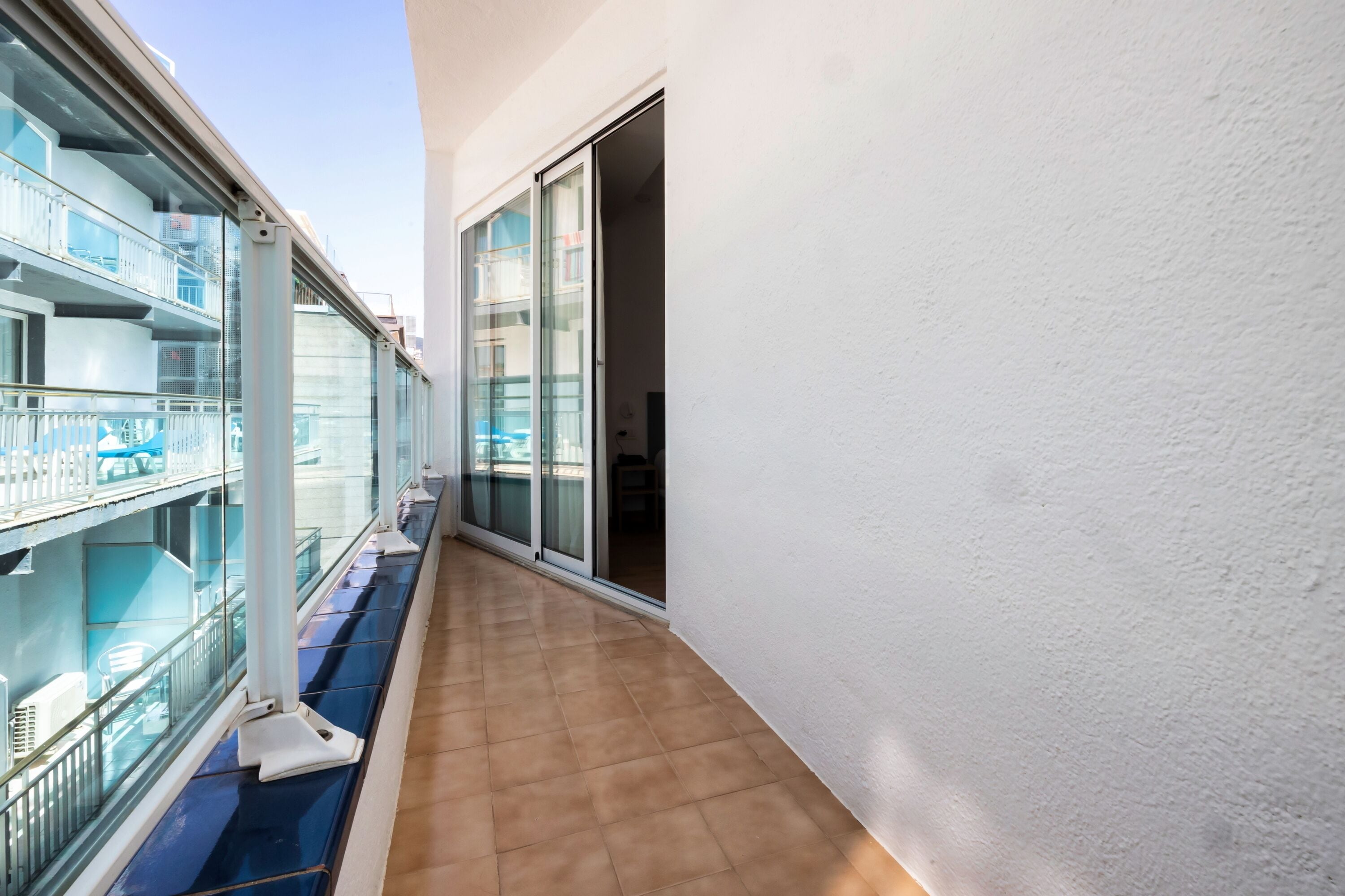 A narrow corridor with a glass railing on one side and a sliding glass door on the other.