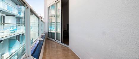 A narrow corridor with a glass railing on one side and a sliding glass door on the other.