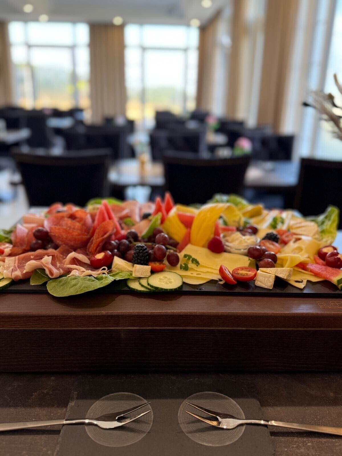 A buffet spread with various cheeses, fruits, and meats.