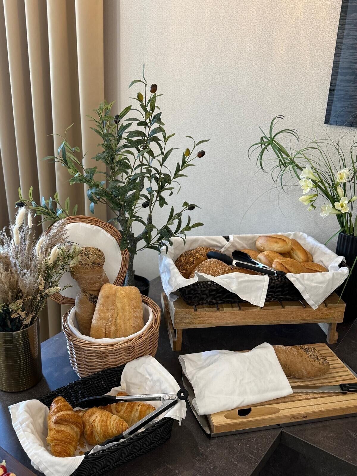 A breakfast setup with bread, croissants, and a plant.
