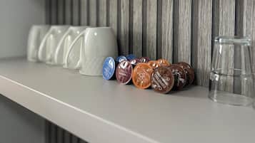 A shelf with coffee capsules and a glass.