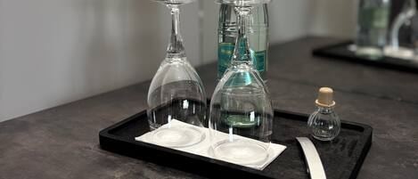 A tray with two wine glasses, a bottle, and a small bottle on a dark countertop.