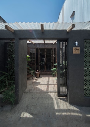 A covered entrance with a metal gate, a tiled floor, and a sign with a date. - Ngâu House (Hue)