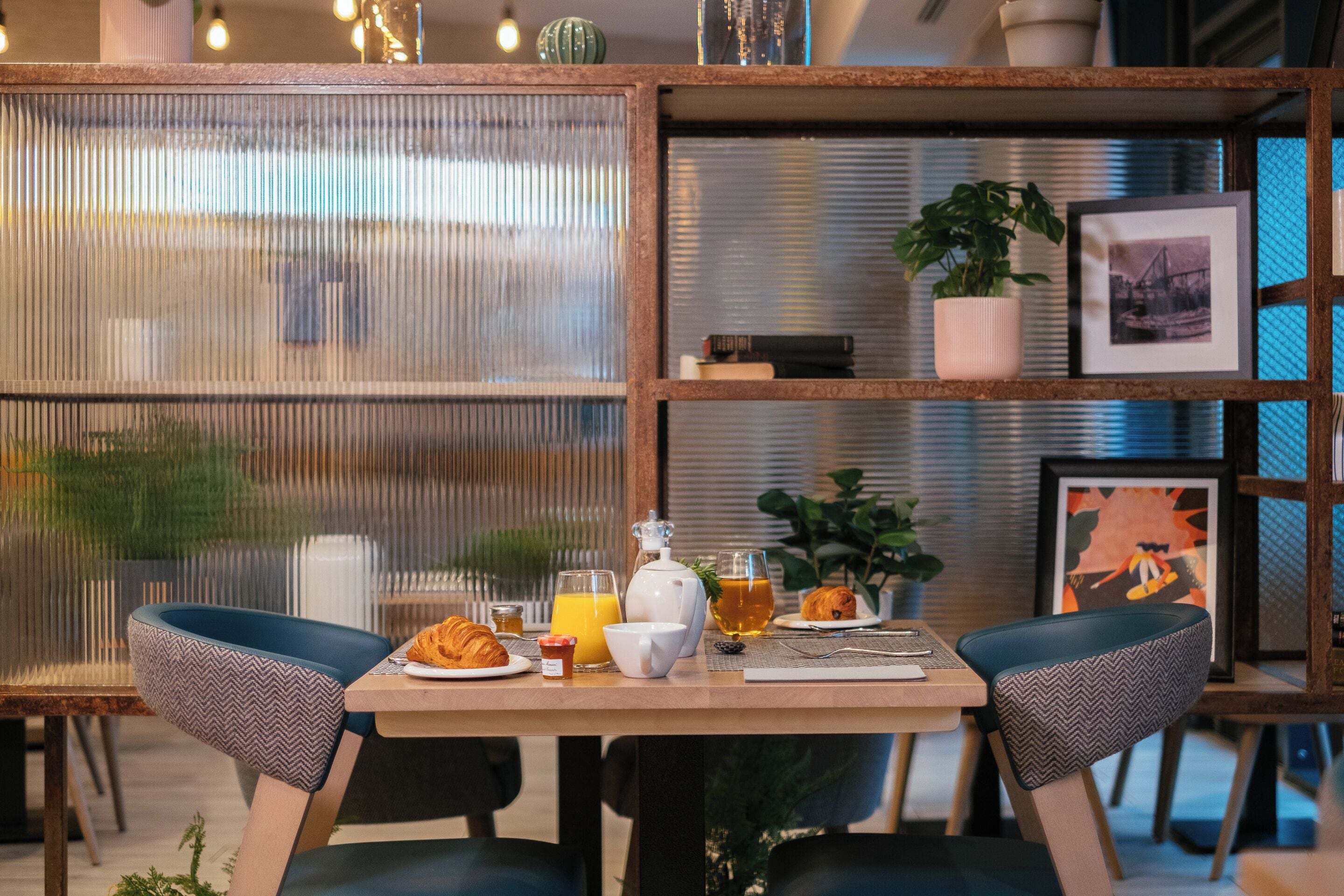 A breakfast table with croissants, orange juice, and a teapot.