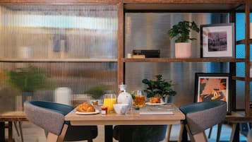 A breakfast table with croissants, orange juice, and a teapot.