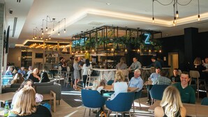 A modern restaurant with a bar area, seating for guests, and a visible 'Z' neon sign.