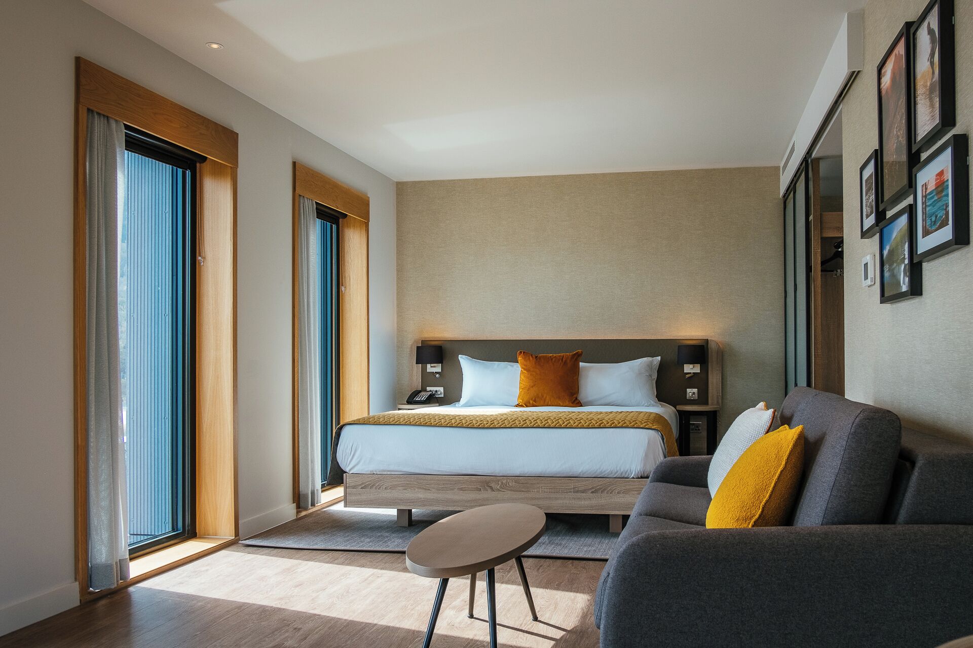 Une chambre d’hôtel moderne avec un grand lit, un canapé, une petite table et une grande fenêtre.