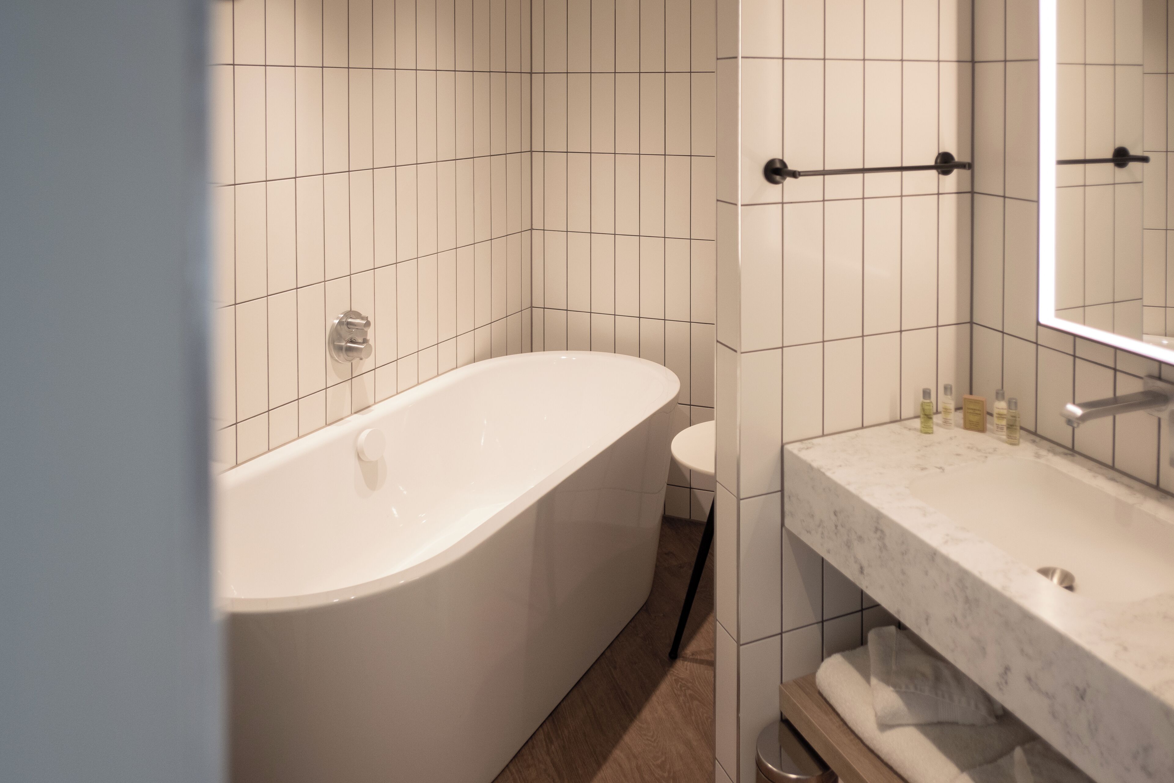 A modern bathroom with a freestanding bathtub, a toilet, and a vanity with a mirror.