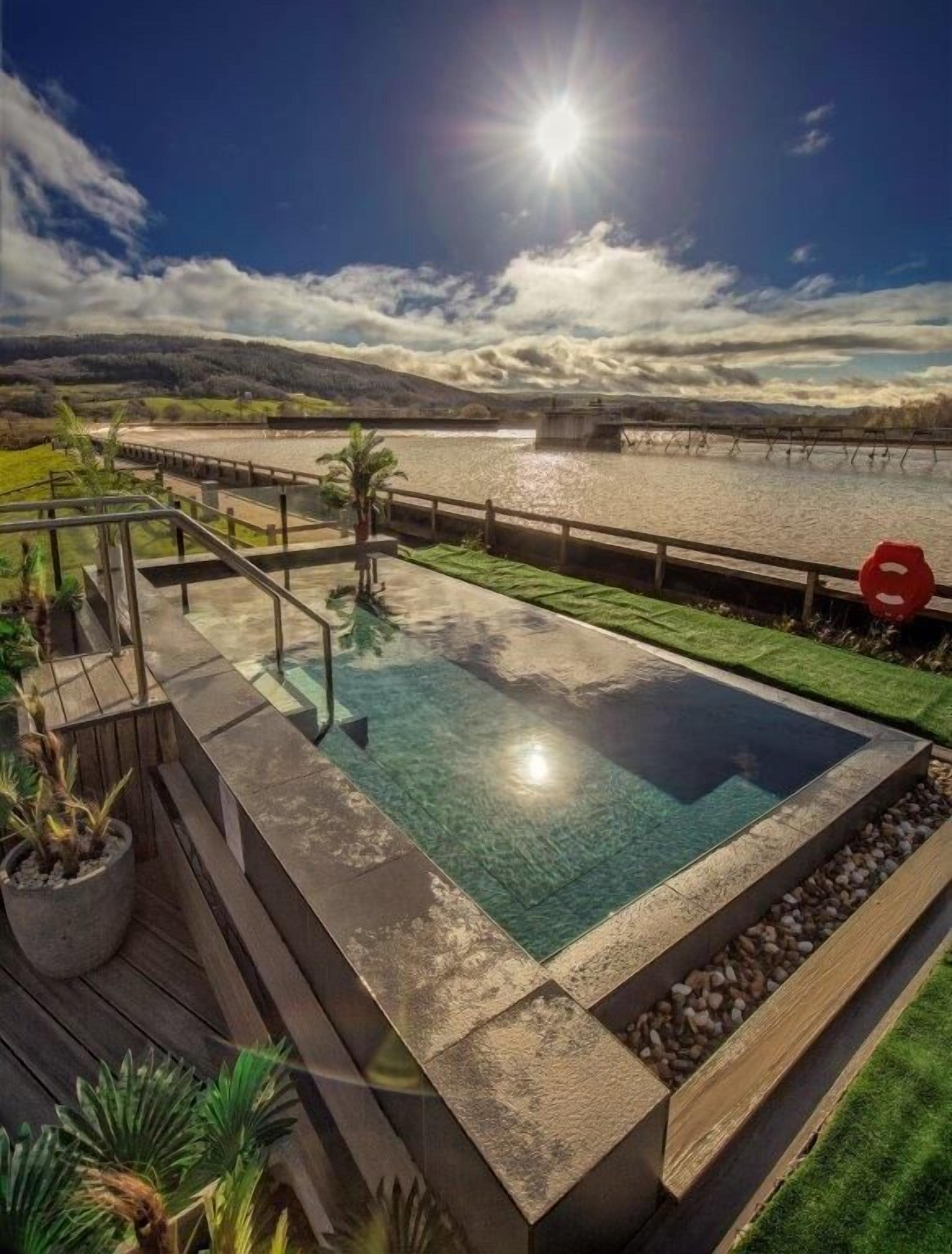 A rectangular infinity pool with a clear view of the water and a distant shoreline.
