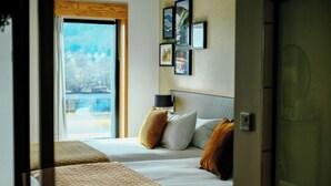 A hotel room with a bed, a bedside table with a lamp, and a view of the outdoors.