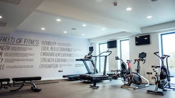 A modern gym with treadmills, stationary bikes, and a bench.