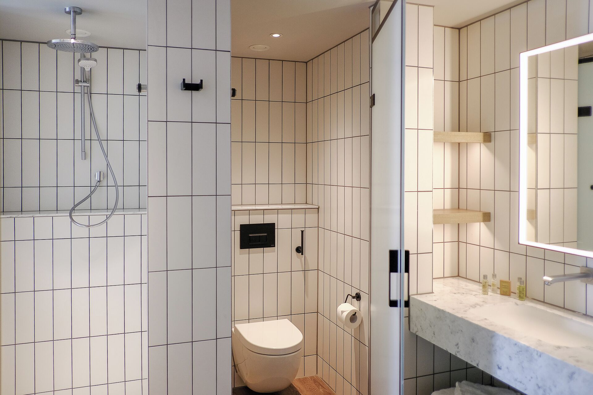Un baño moderno con ducha, inodoro y tocador con espejo.