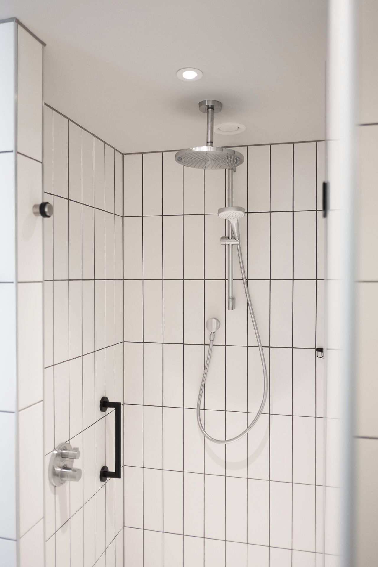 A modern shower with a handheld showerhead and a wall-mounted control panel.