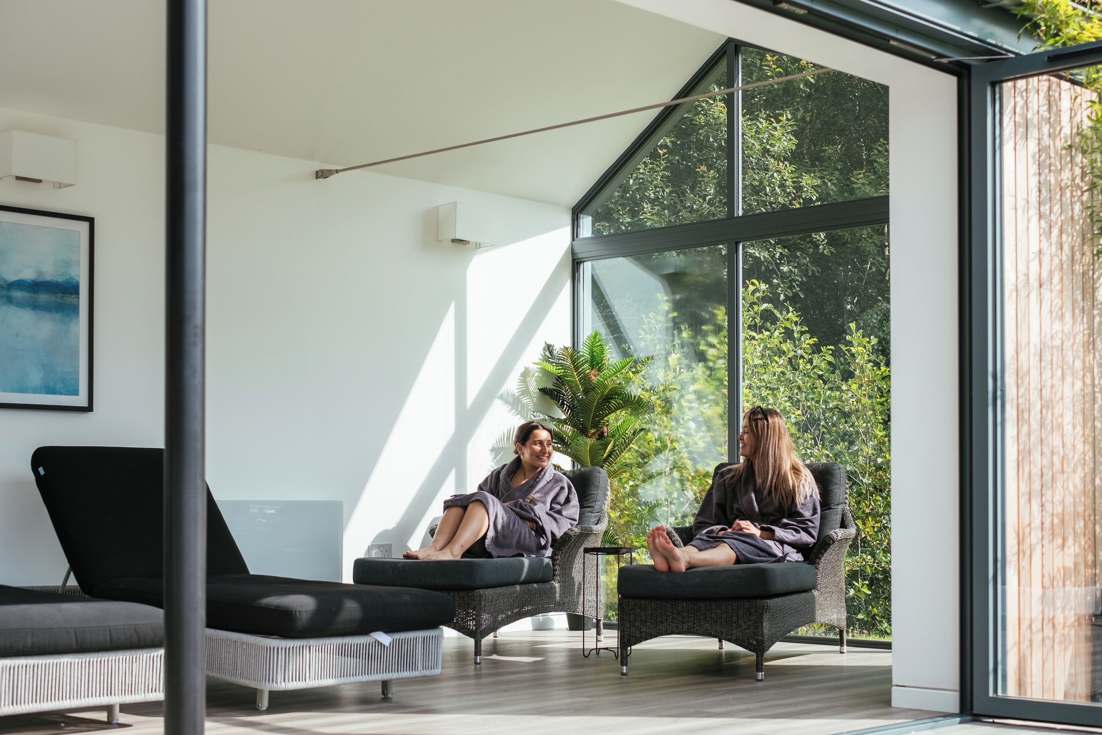 Una habitación moderna con ventanas amplias, un sofá y una silla.